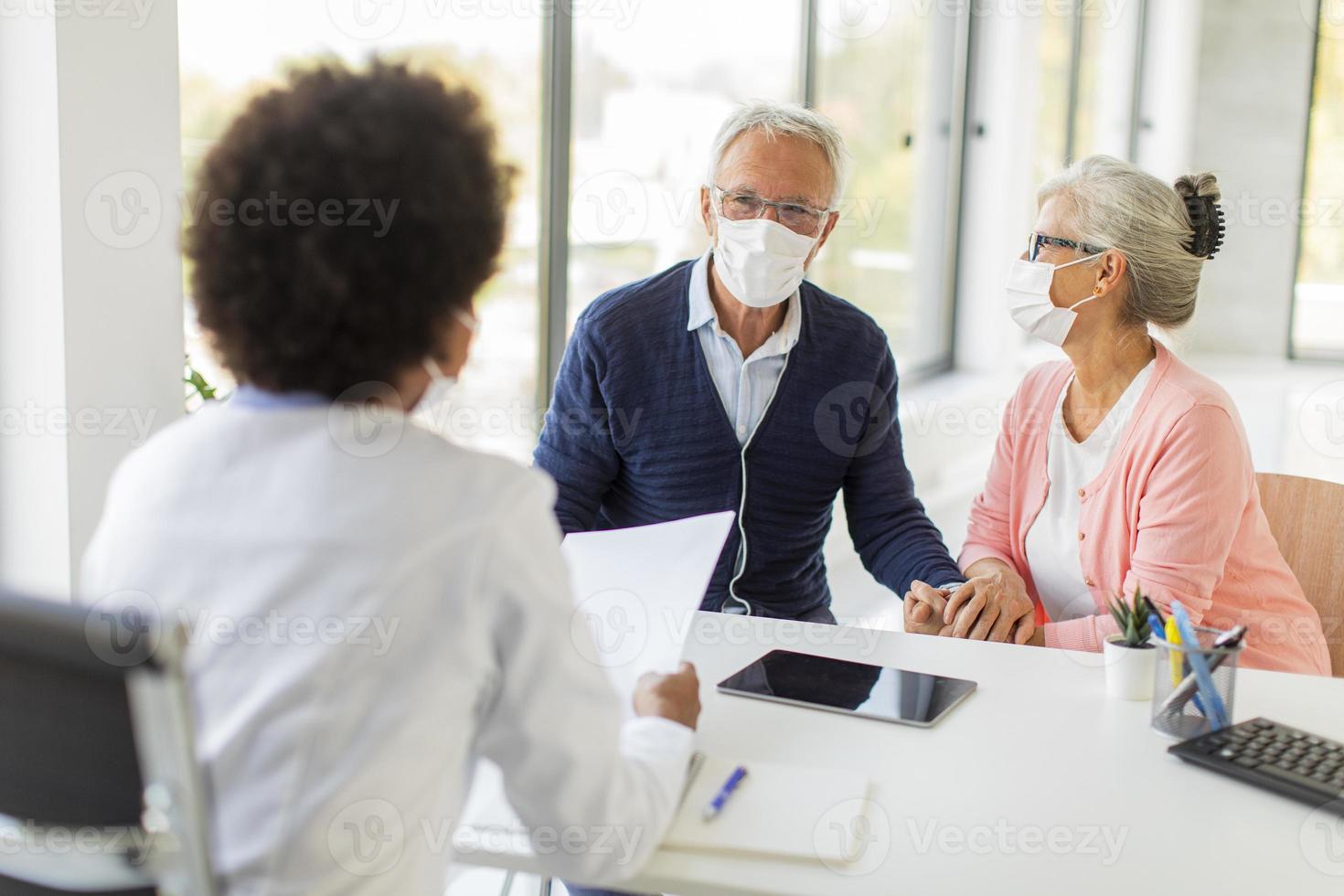 médecin parle à un couple mature masqué photo