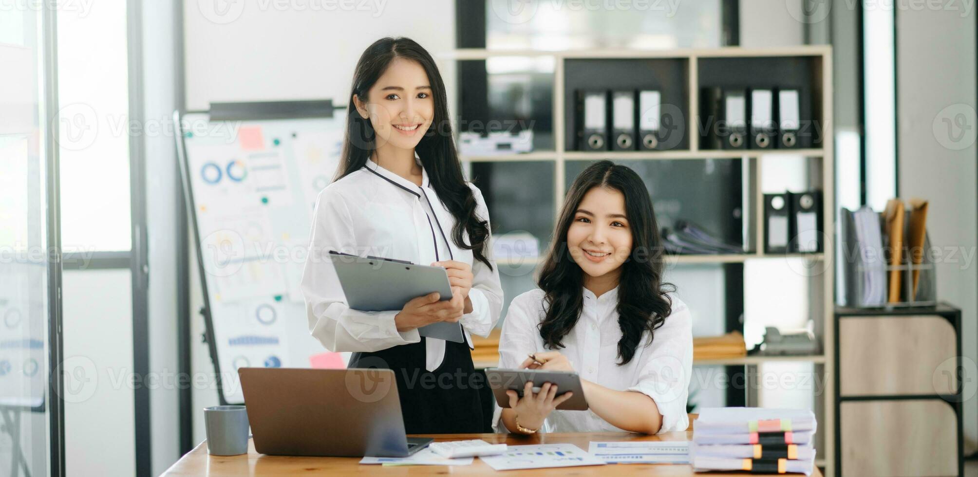 deux asiatique femme d'affaires discuter investissement projet travail et Planification stratégie avec tablette portable ordinateur dans bureau. photo