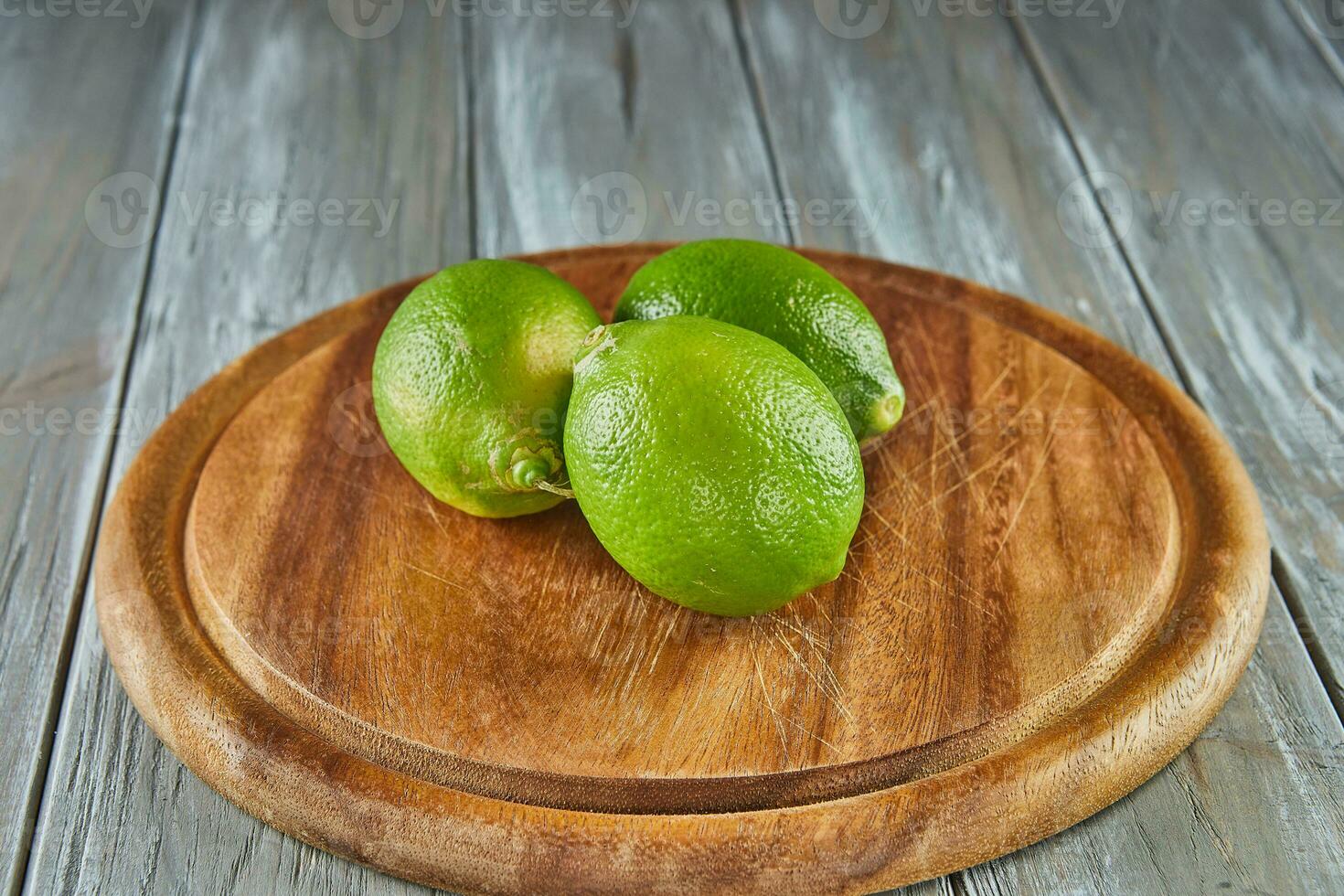 citrons verts sur en bois supporter sur gris en bois Contexte photo