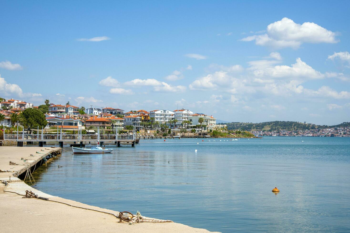 une promenade dans Turquie, ayvalik ville. une bateau et Maisons sur le de la ville front de mer sur une ensoleillé été journée. photo