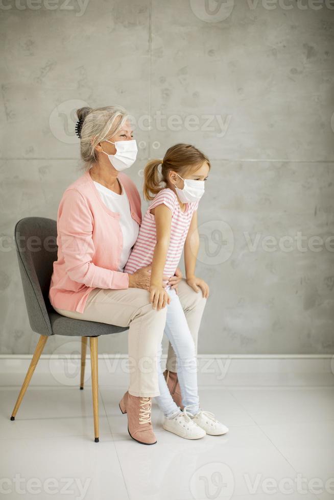 grand-mère sur une chaise avec petite-fille portant des masques photo