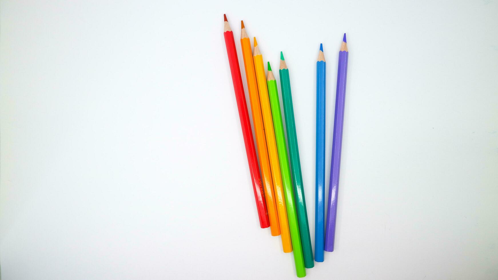 coloré des crayons dans rangée sur une blanc Contexte Haut voir. photo