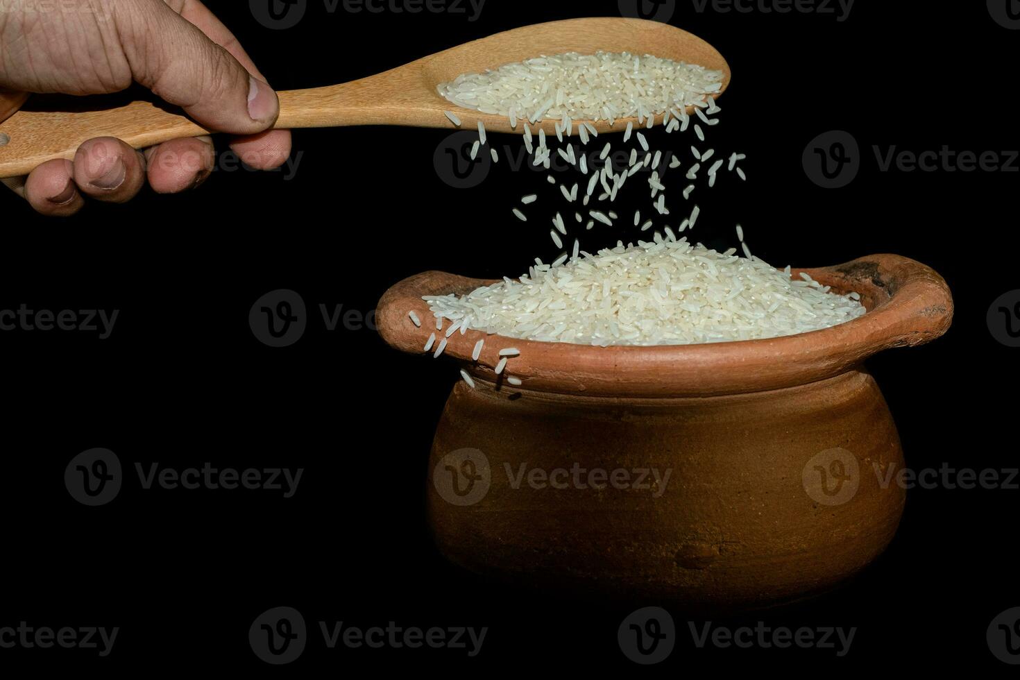 ramasser du riz à l'aide d'une louche dans un pot en argile photo