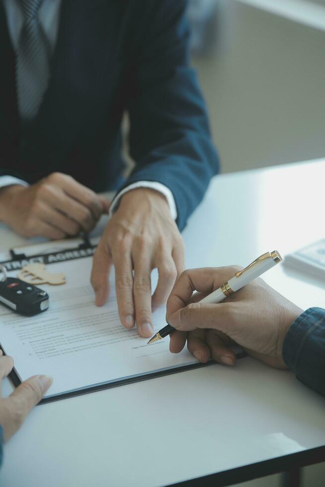 fermer asiatique Masculin gens voiture vendeur ou Ventes directeur des offres à vendre une voiture et explique et lit le termes de signature une voiture Contrat et assurance. photo