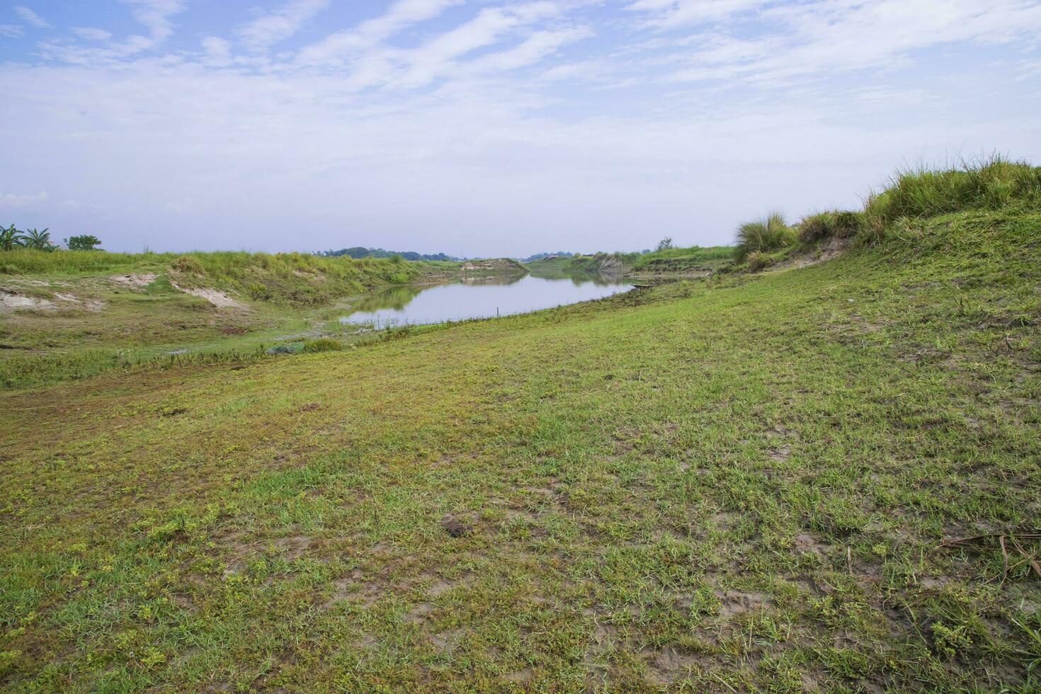 canal avec de l'herbe verte et de la végétation reflétée dans l'eau à proximité de la rivière padma au bangladesh photo