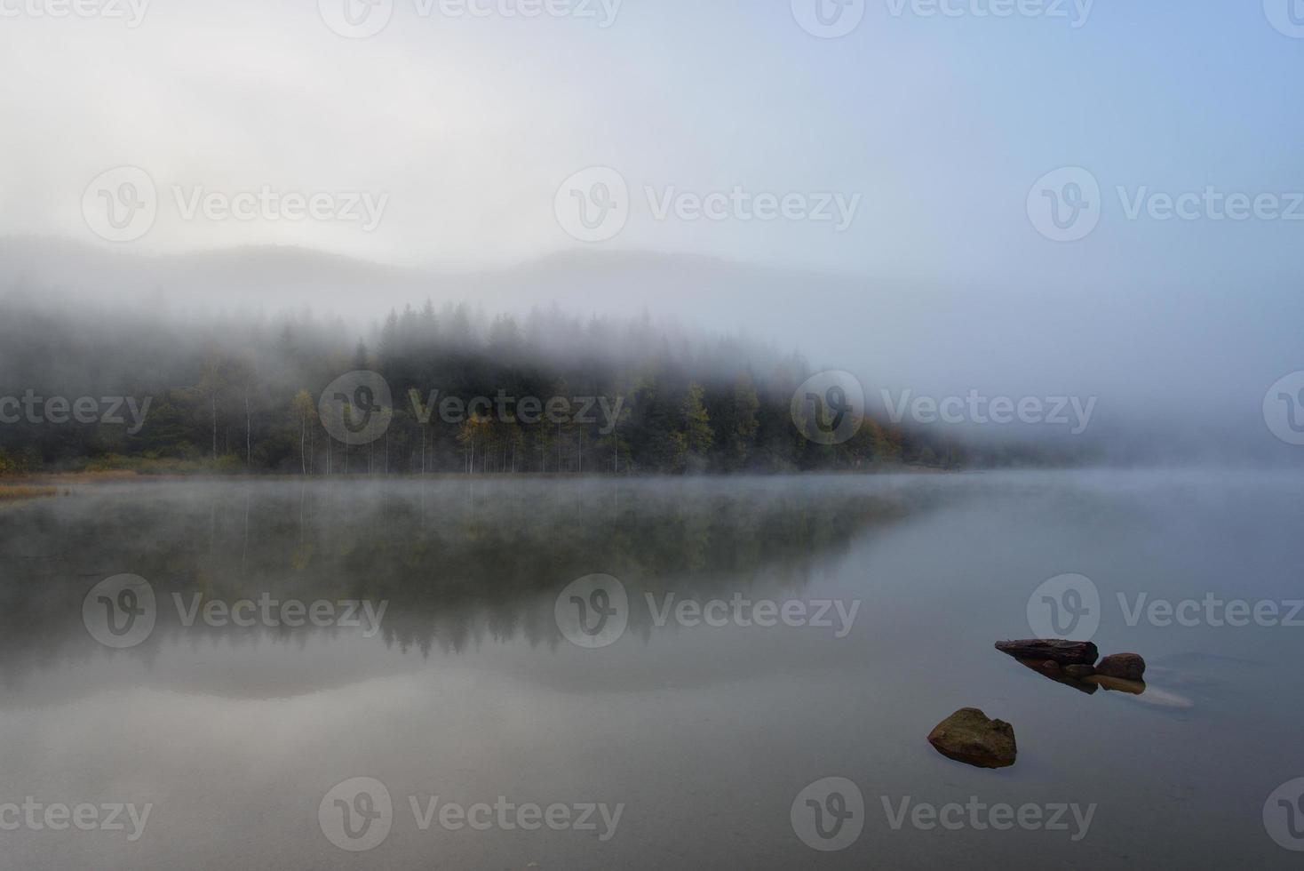 Paysage d'automne dans les montagnes avec des arbres se reflétant dans l'eau au lac de st ana roumanie photo