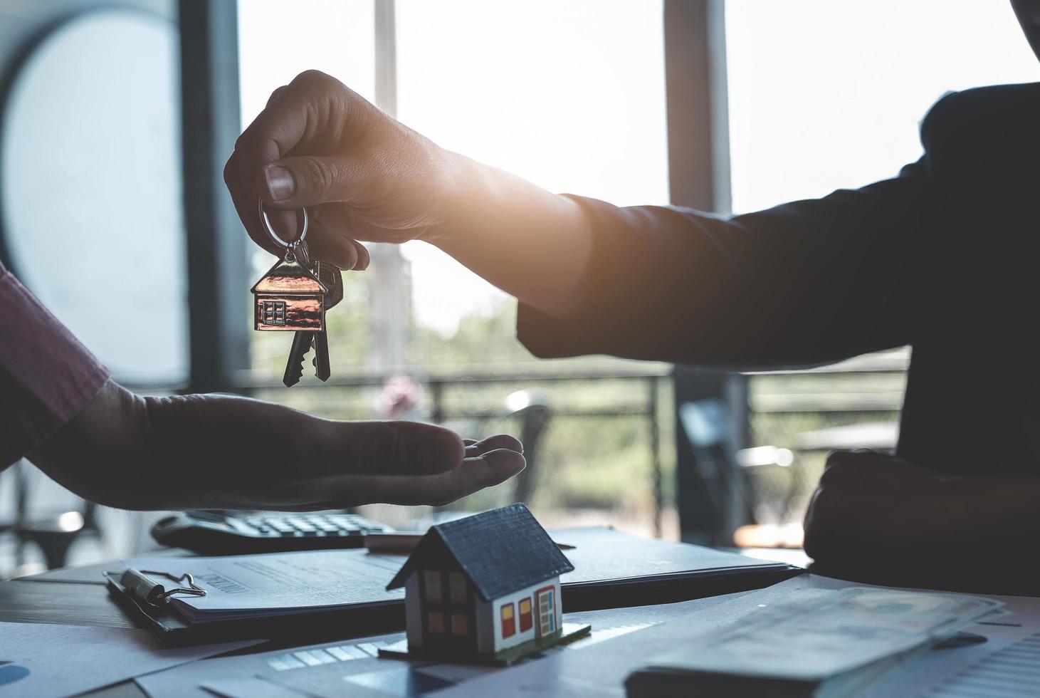 les agents immobiliers s'engagent à acheter une maison et à remettre les clés aux clients dans les bureaux de leur agence. accord de concept photo