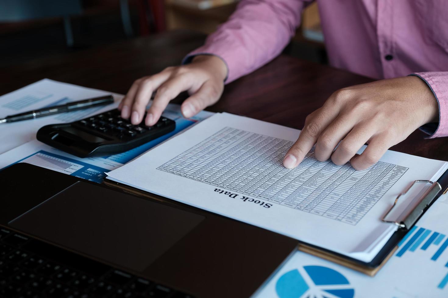 Concept d'analyse boursière, homme à l'aide d'une calculatrice et d'un ordinateur portable pour analyser l'application de données de graphique boursier au bureau. photo