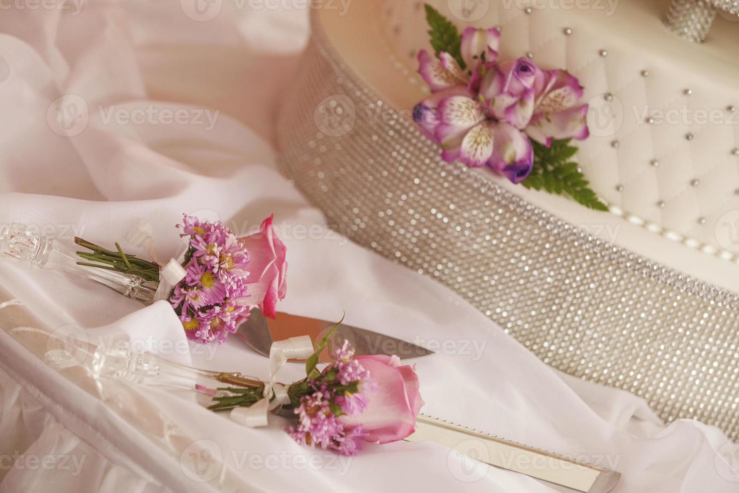 gâteau de mariage blanc décoré de fleurs et jeu de couteaux photo