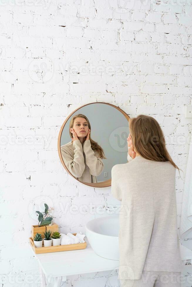 femme à la recherche à le miroir, fabrication en haut dans le Matin photo