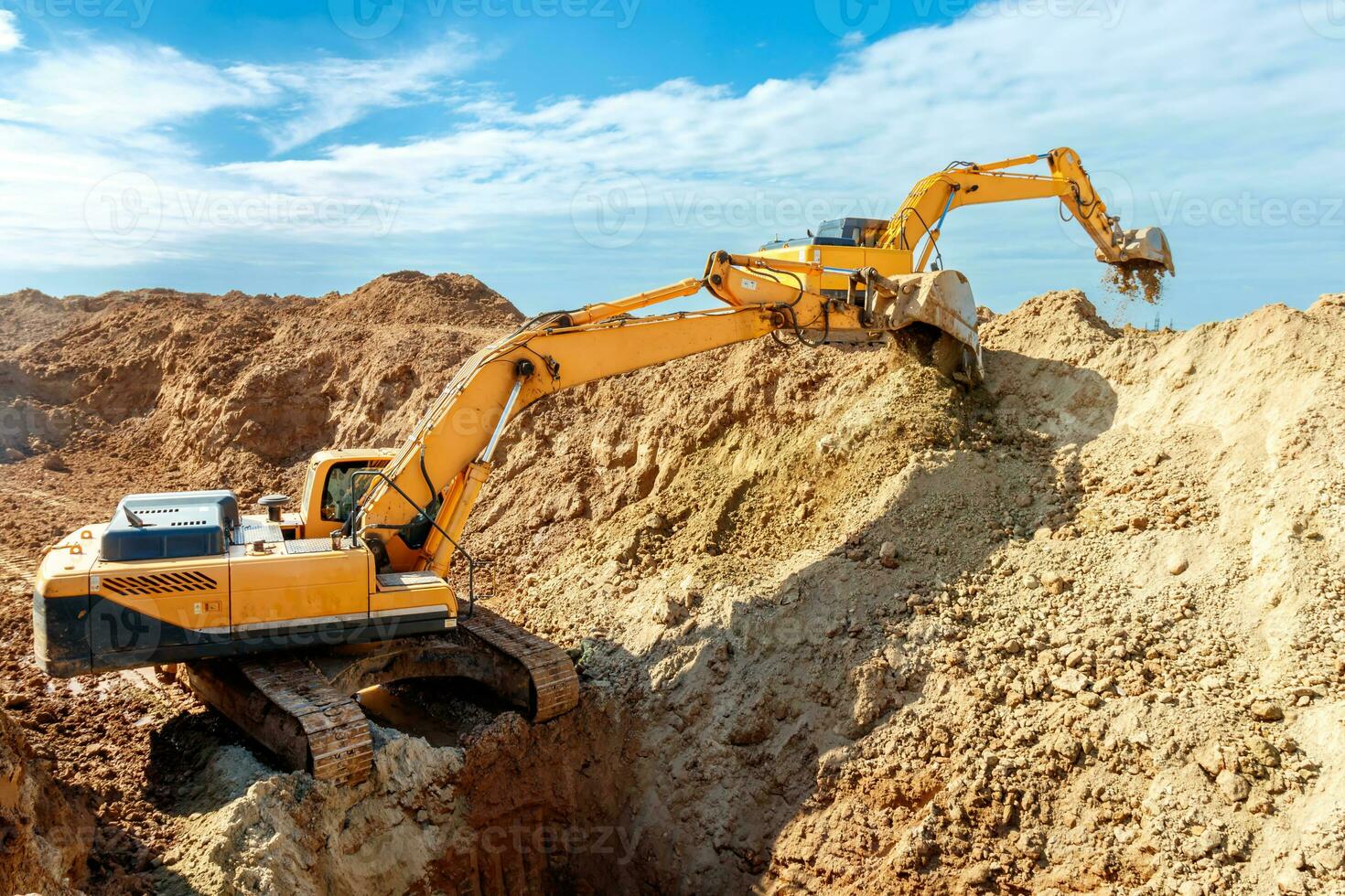 deux excavatrice sont creusement sol dans le construction site sur ciel arrière-plan, avec blanc duveteux nuage photo