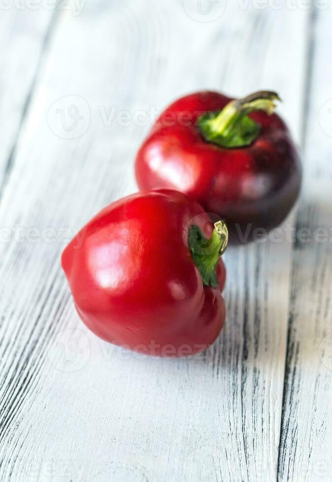 Frais rouge cloche poivrons sur le en bois table photo