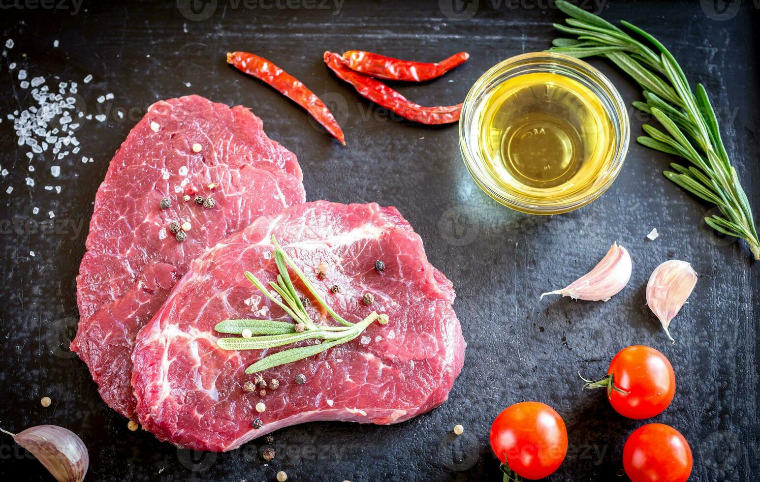 steaks de boeuf frais avec des ingrédients sur le fond sombre photo