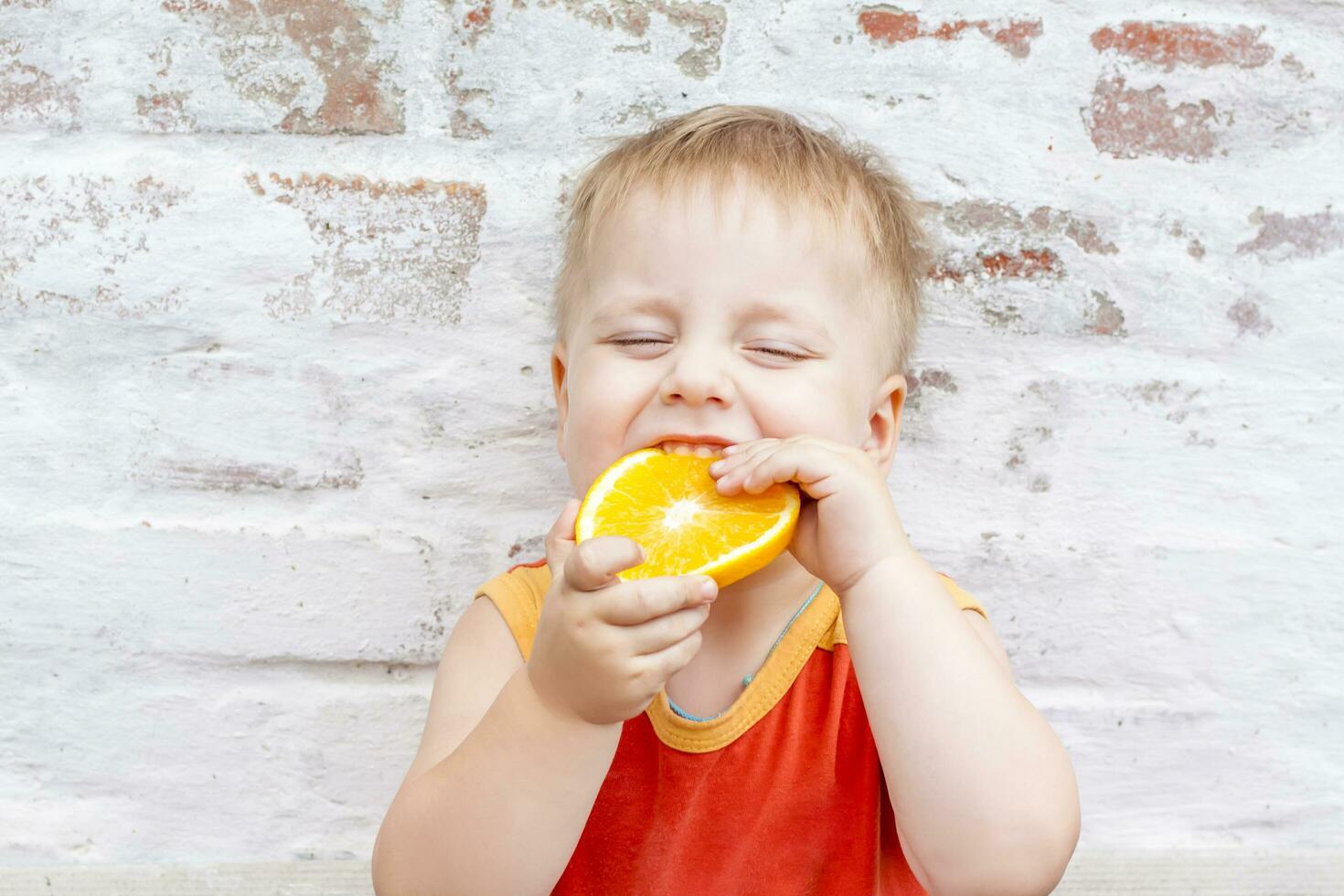 portrait de enfant. mignonne garçon posant avec un orange. le émotions de une enfant. photo
