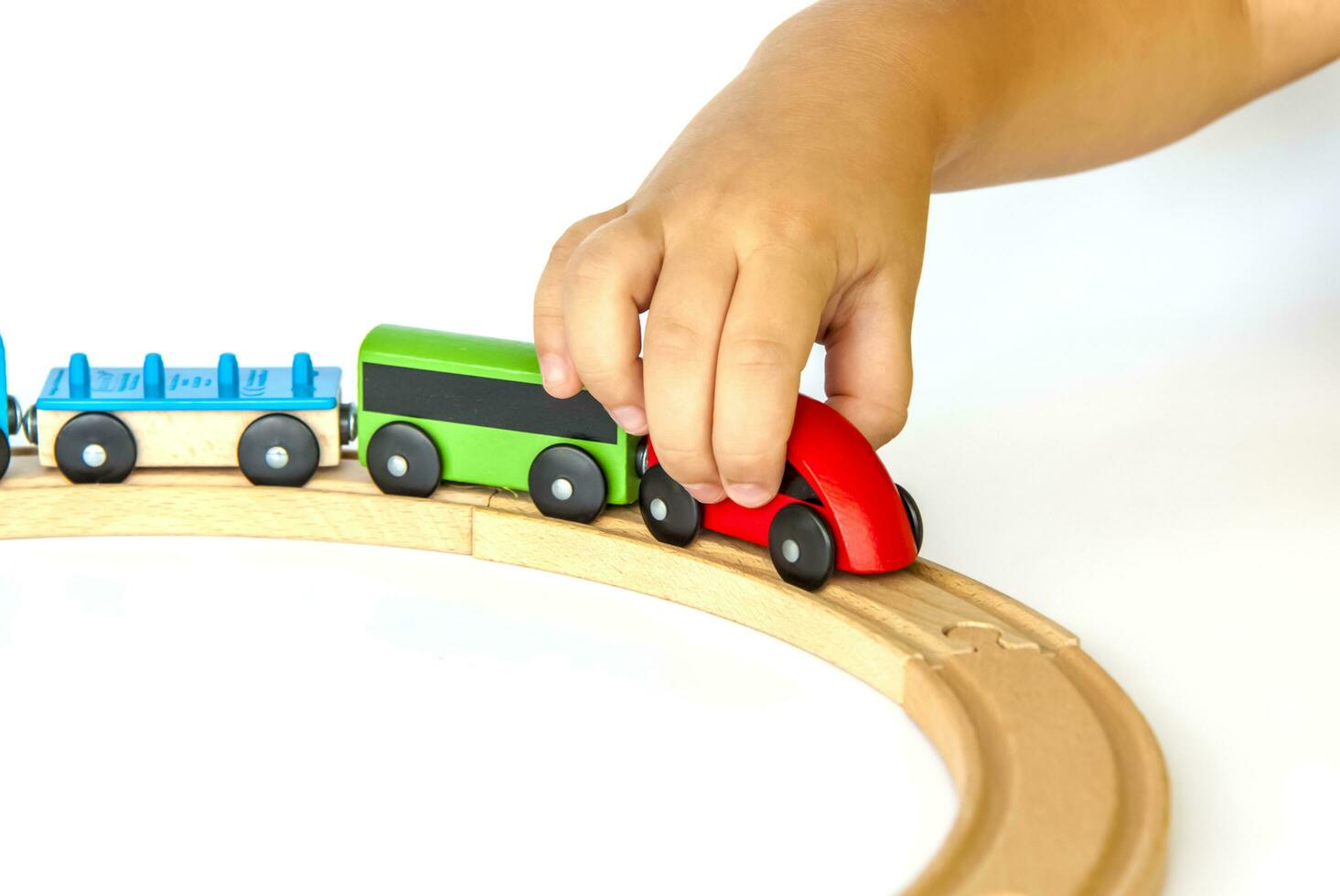 une enfant pièces avec une train fabriqué de bois. fermer de une enfant main. photo