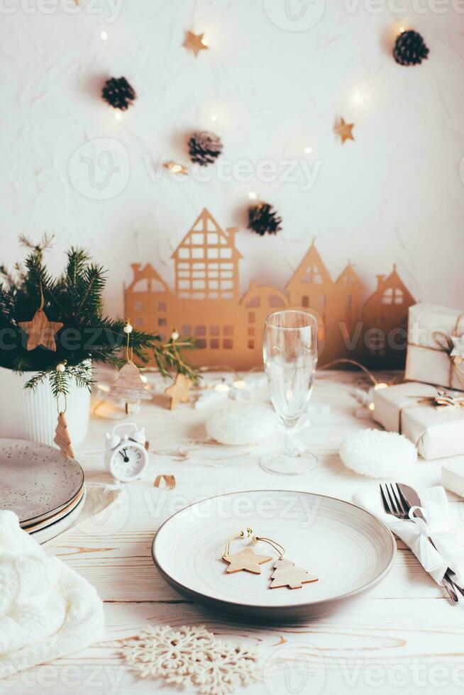 organisation de une de fête Noël tableau. plaque, coutellerie, Champagne verre et Noël décorations. paysages de table sur blanc en bois tableau. verticale vue photo