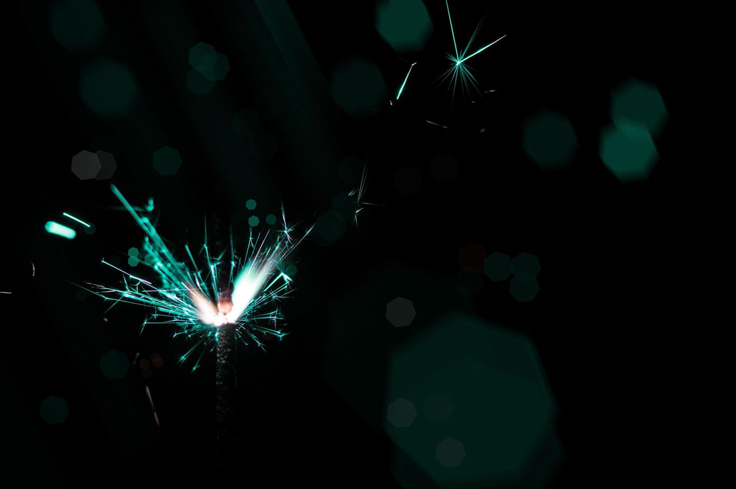 Sparkler en lumière turquoise et blanche sur fond noir photo