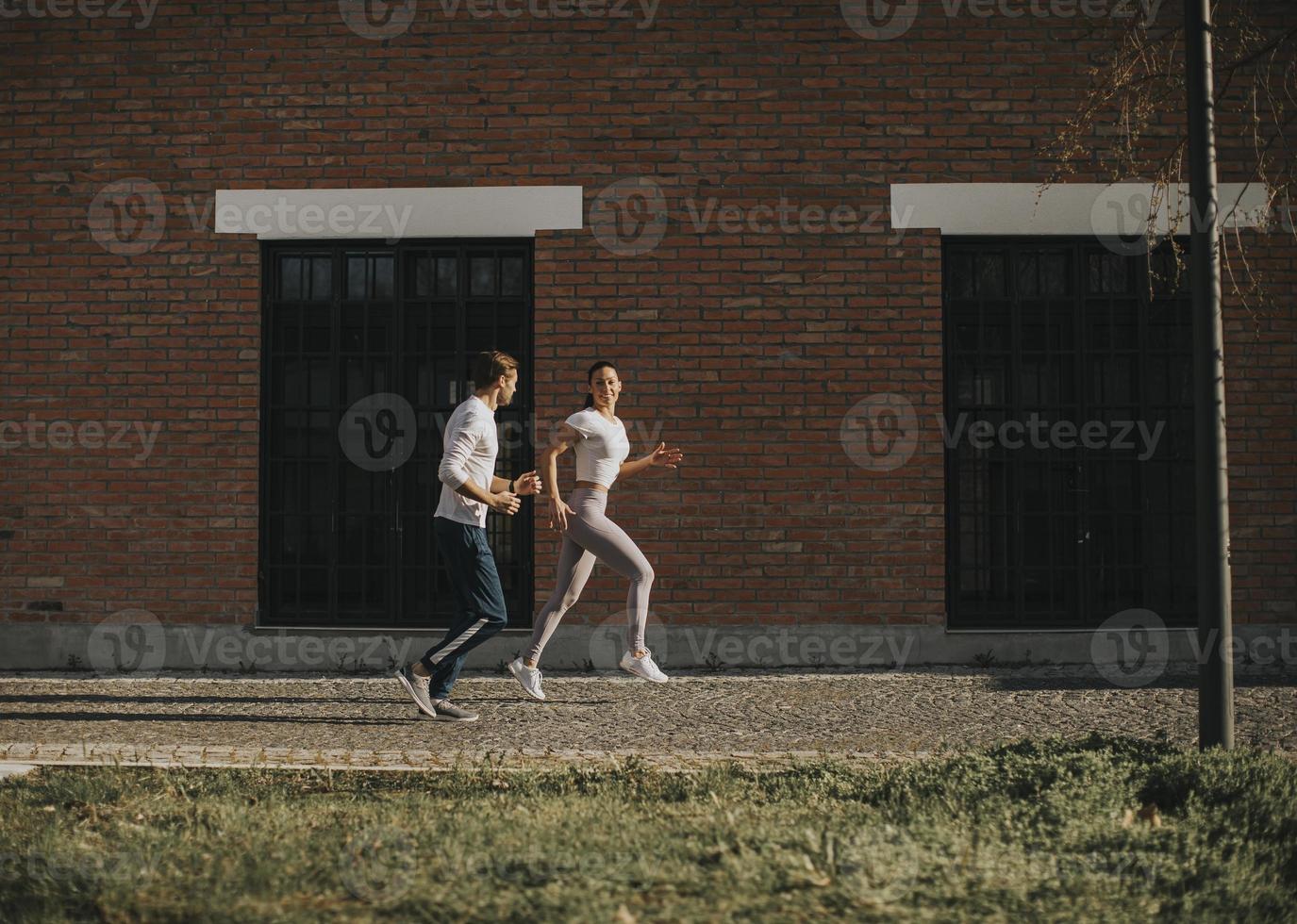 jeune couple en cours d'exécution dans l'environnement urbain photo