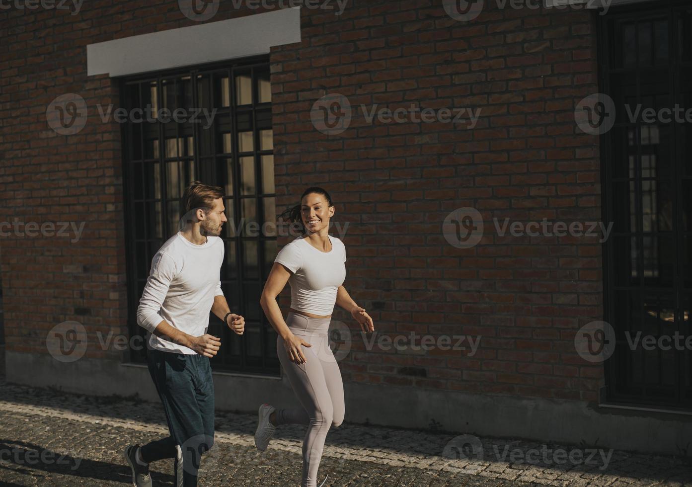 jeune couple en cours d'exécution dans l'environnement urbain photo