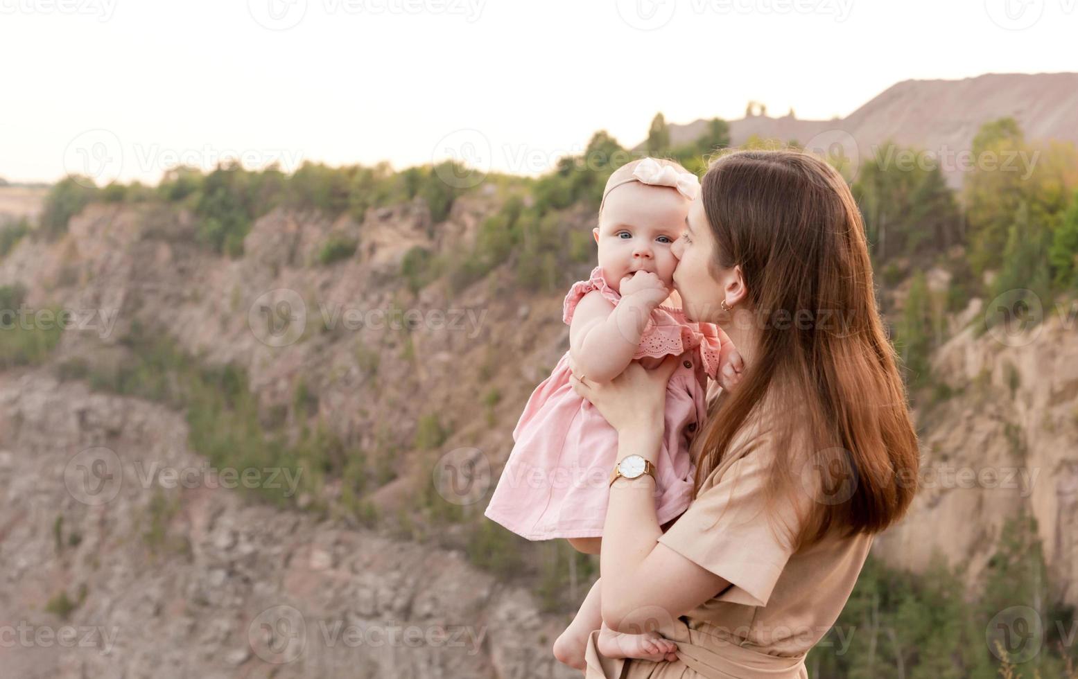 maman tient un enfant dans ses bras et l'embrasse doucement sur la joue à l'extérieur photo