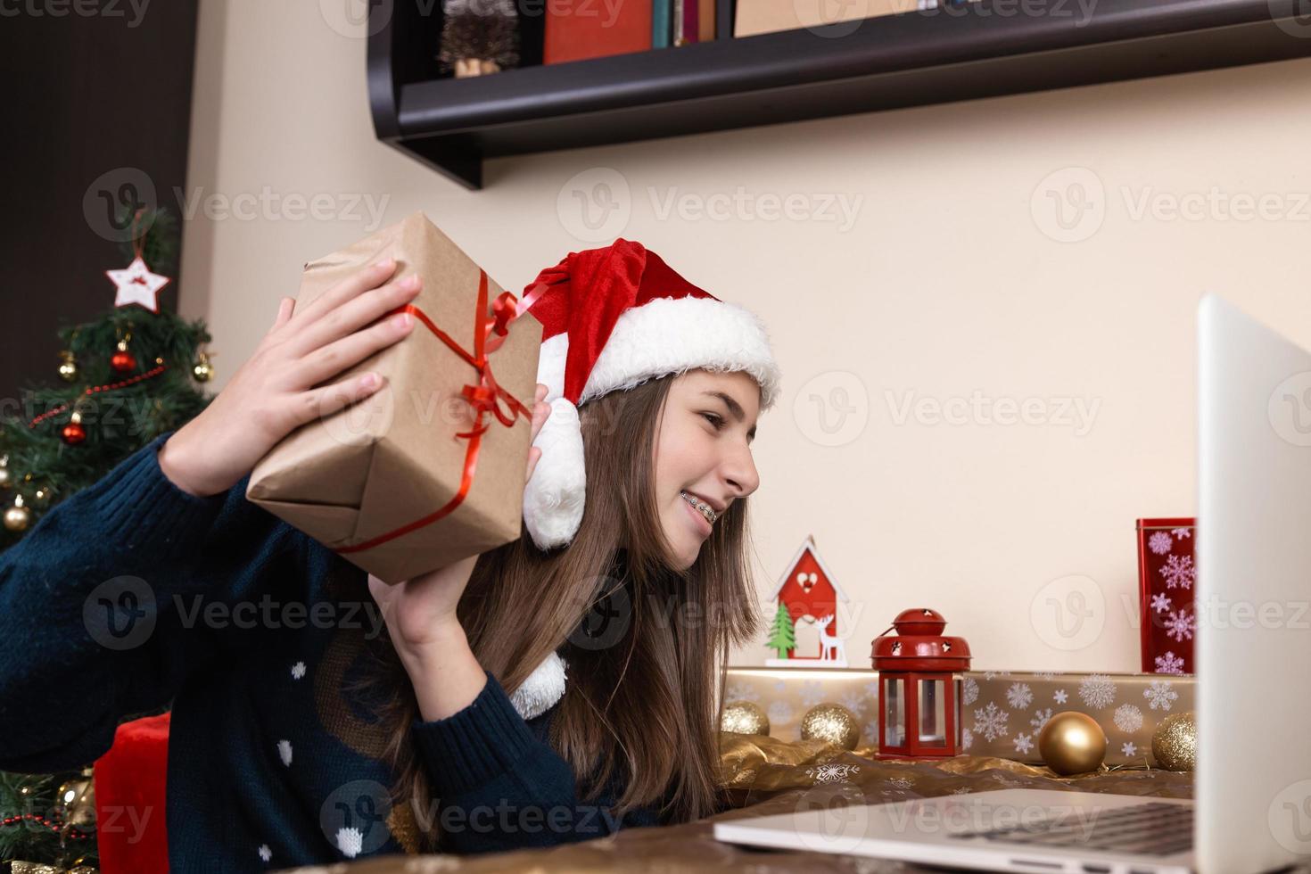 fille en chapeau de père noël utilisant un ordinateur portable pour un appel vidéo aux amis et aux parents photo