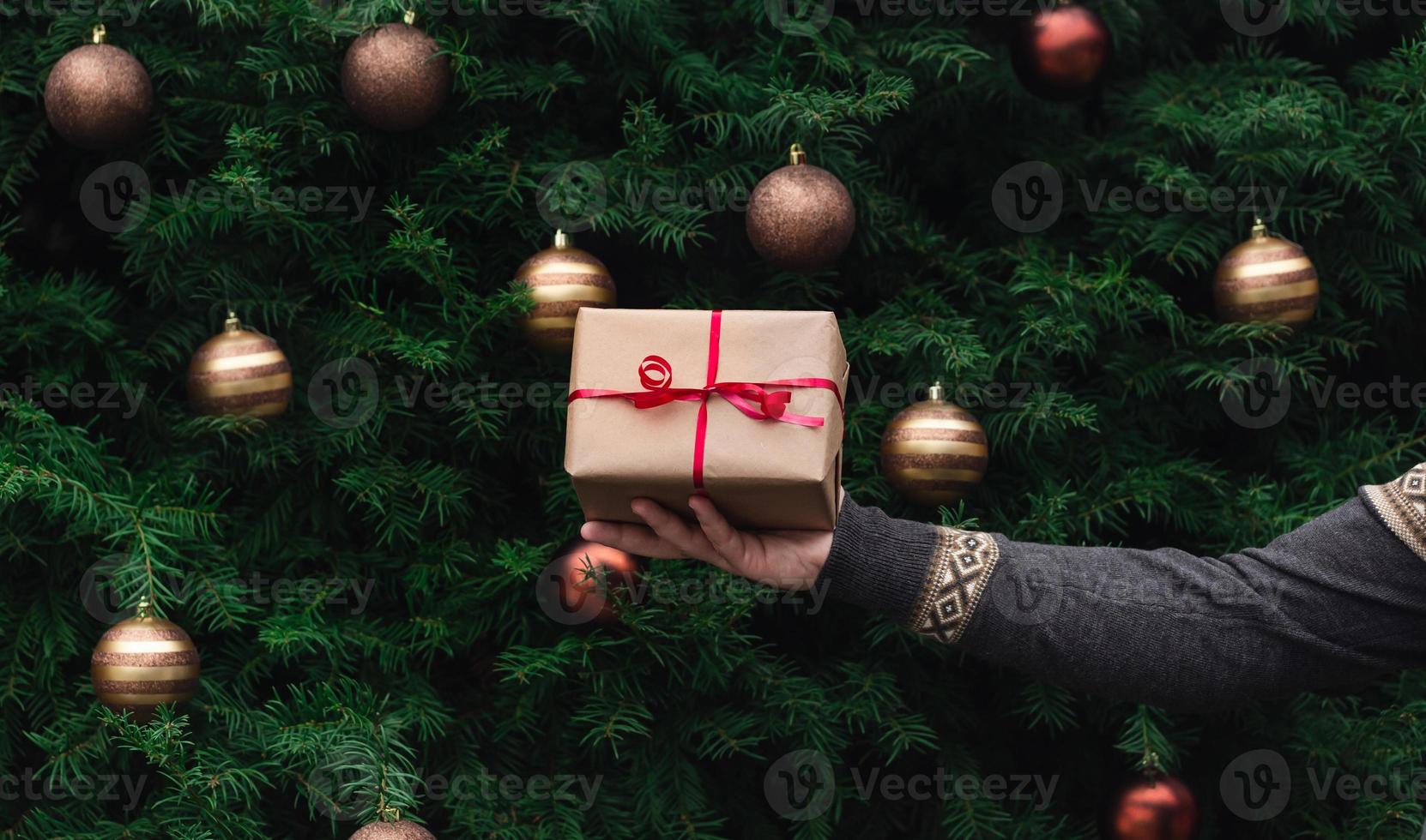 La main masculine en pull tricoté détient une boîte-cadeau en papier kraft photo