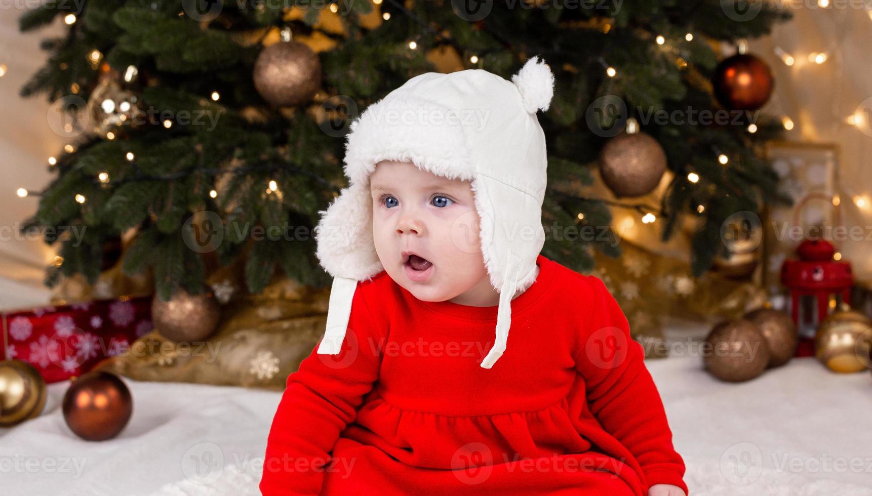 une jolie petite fille dans une robe rouge et un chapeau blanc exprime des émotions photo