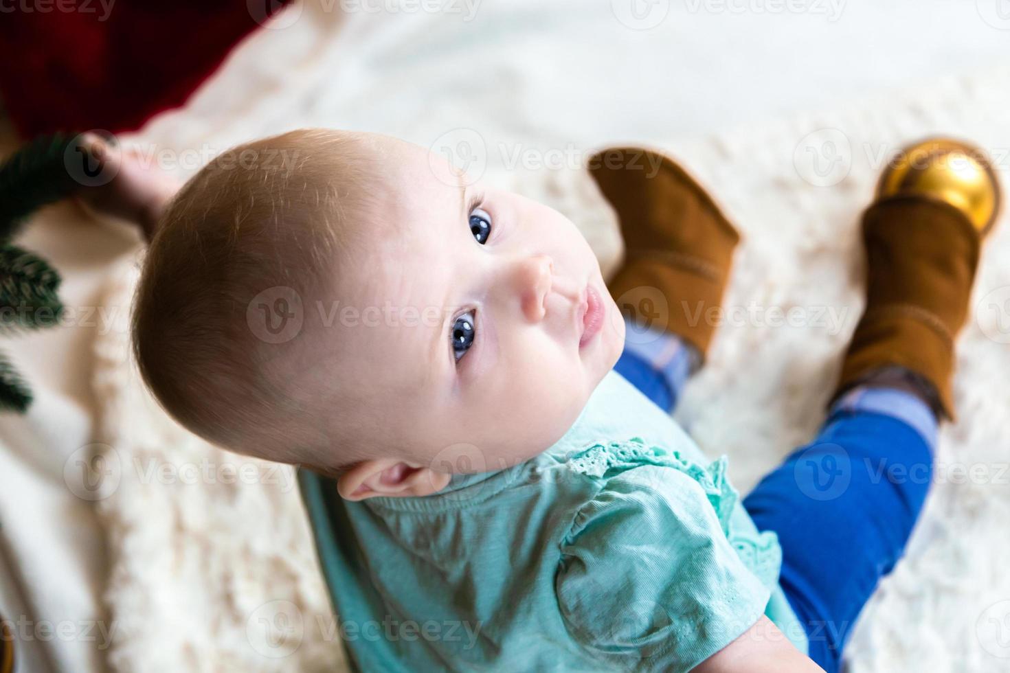 Vue de dessus bébé en jeans et chaussures se trouve près d'un arbre de Noël photo