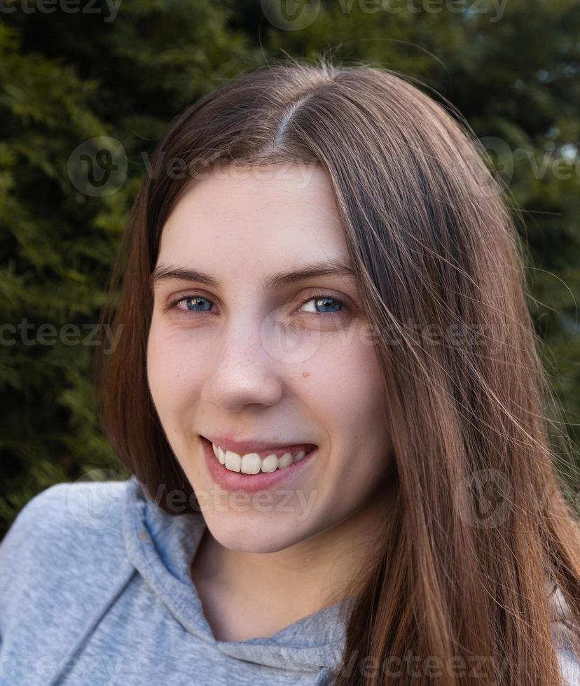 Femme souriante avec un sourire parfait et des dents blanches dans un parc et regardant la caméra photo