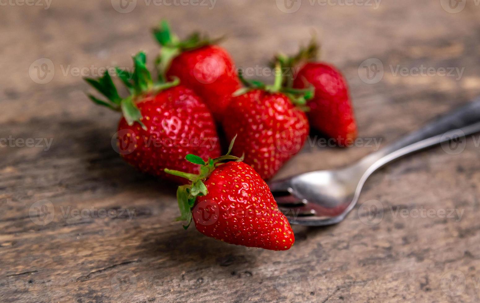 Fraises fraîches et une baie sur la fourche encore la vie sur fond de bois foncé photo