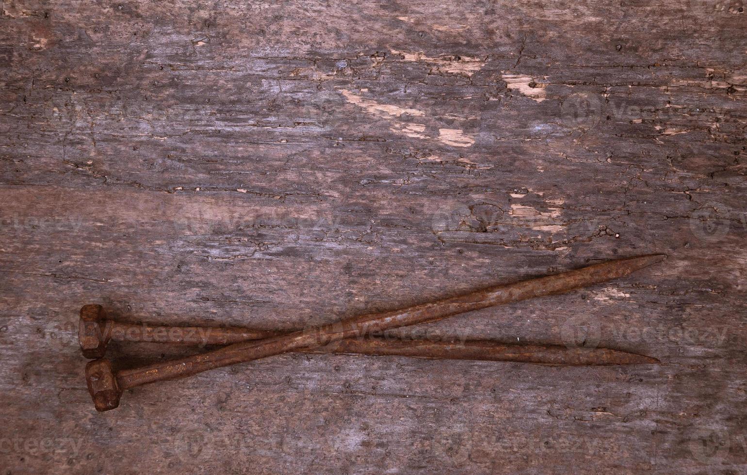 Deux vieux clous rouillés reposent sur un fond de bois photo