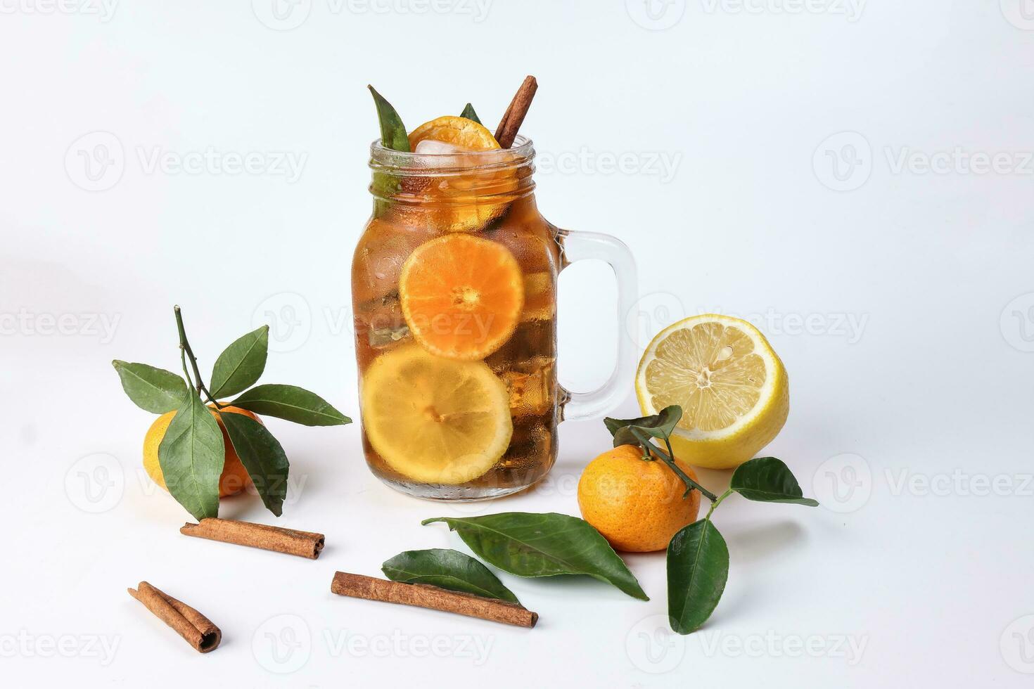 liquide la glace citron Orange thé avec tranche vert feuille cannelle bâton dans transparent verre pot agresser sur blanc Contexte entier fruit photo