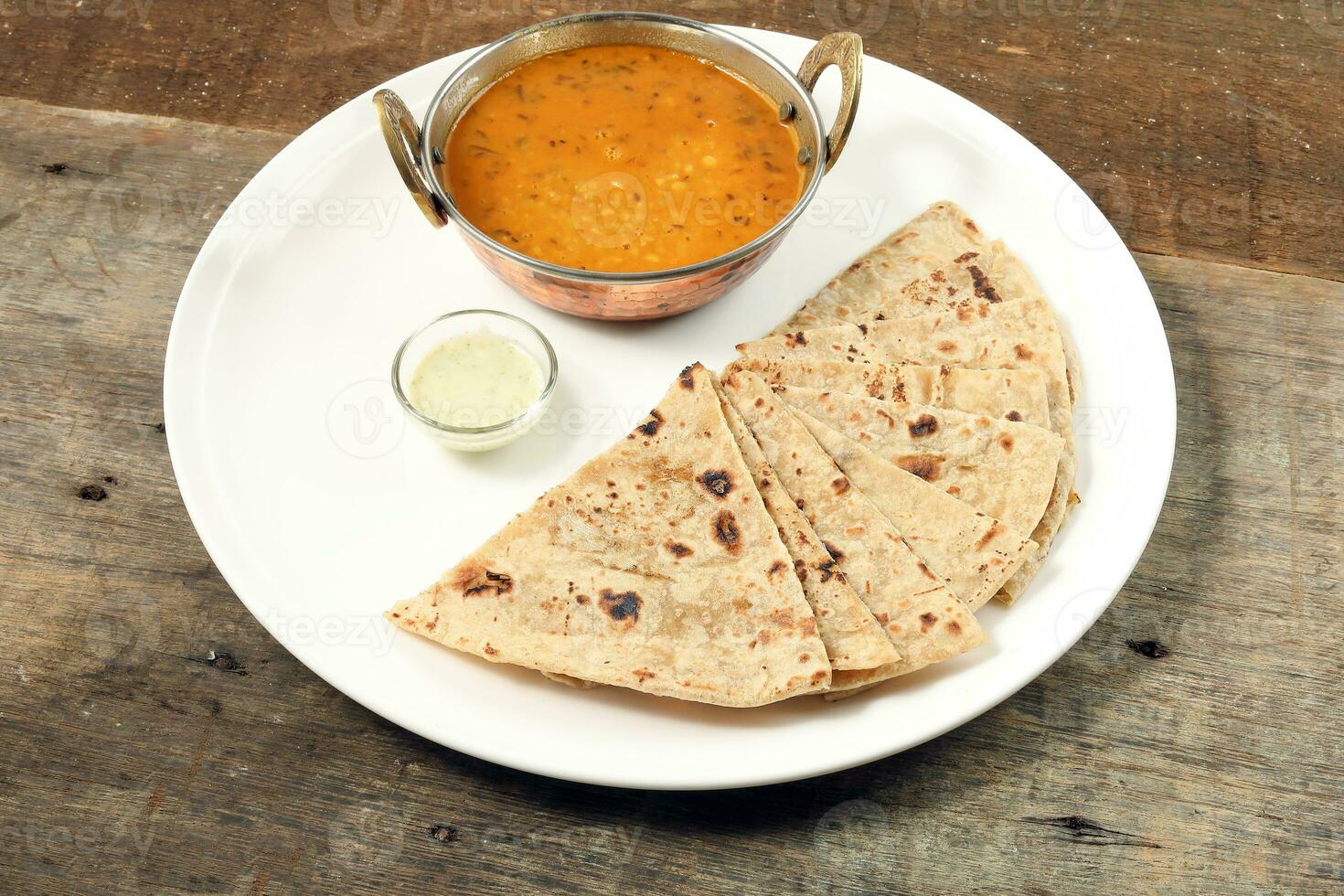 Fait main plat pain chapati et dal tadka frire dans laiton bol la poêle sur blanc assiette rustique en bois Contexte photo