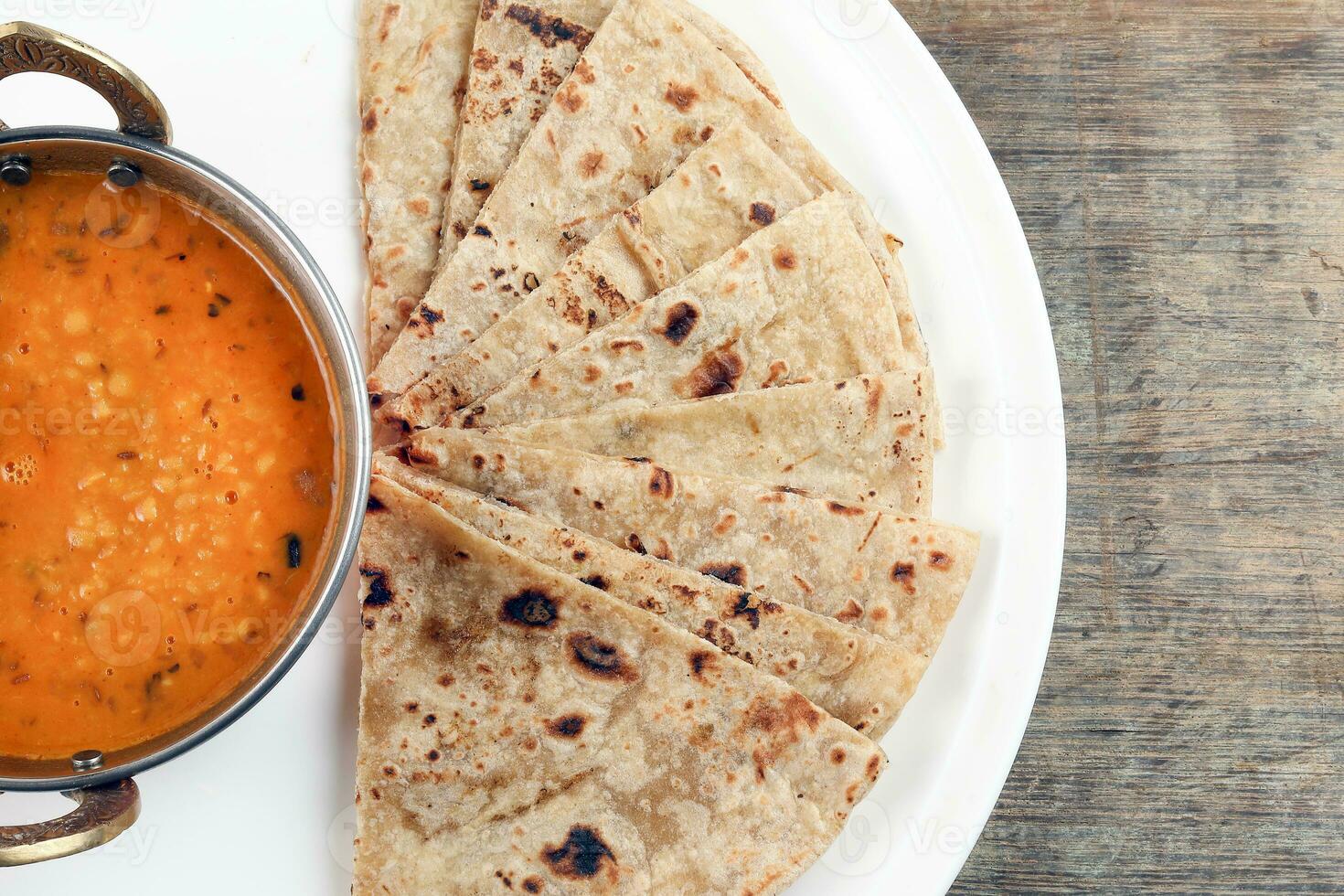 Fait main plat pain chapati et dal tadka frire dans laiton bol la poêle sur blanc assiette rustique en bois Contexte photo