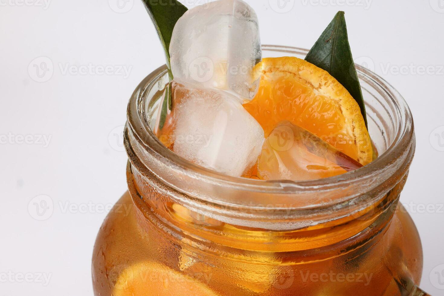 liquide la glace citron Orange thé avec tranche vert feuille cannelle bâton dans transparent verre pot agresser sur blanc Contexte photo