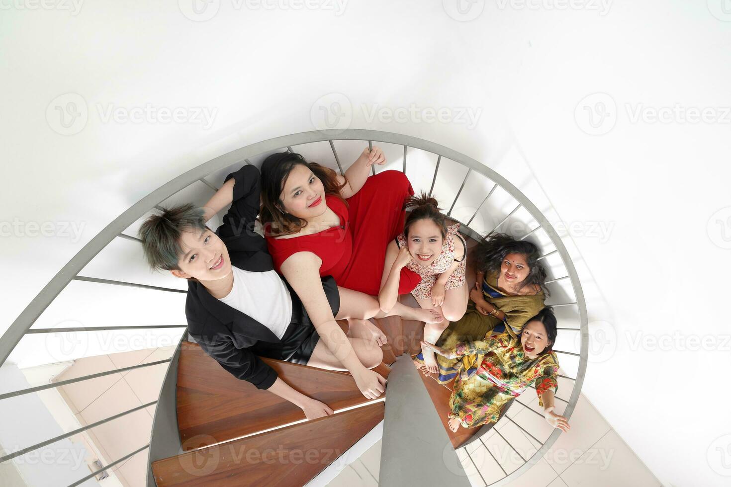 Jeune sud-est asiatique femme groupe séance sur intérieur spirale escalier content prendre plaisir amusement Regardez amusement Haut vue photo