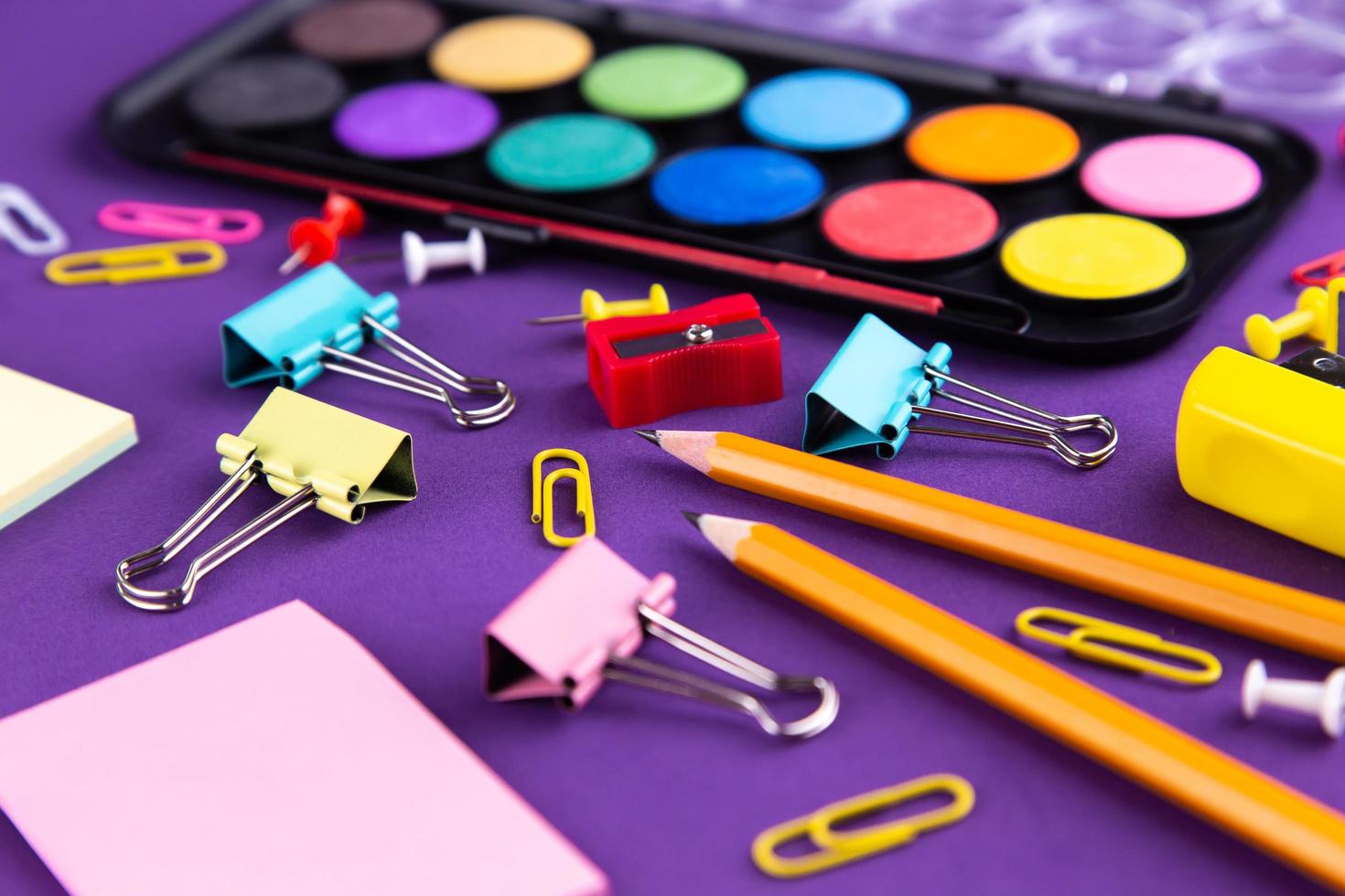 fournitures de bureau scolaire sur un bureau de fond violet photo