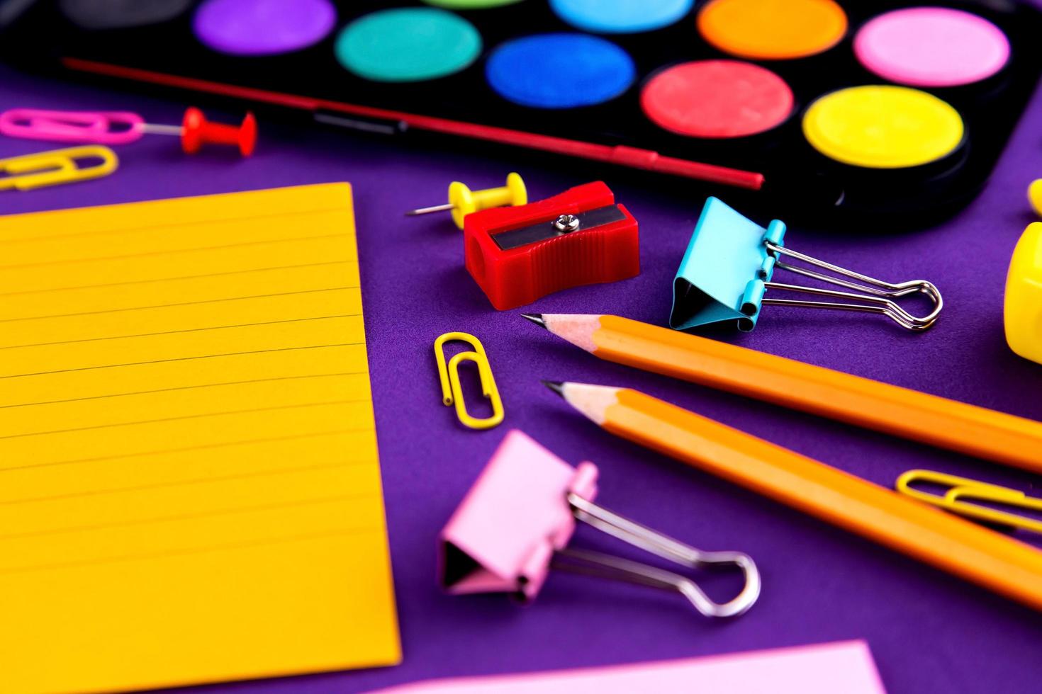 fournitures de bureau scolaire sur un bureau de fond violet photo