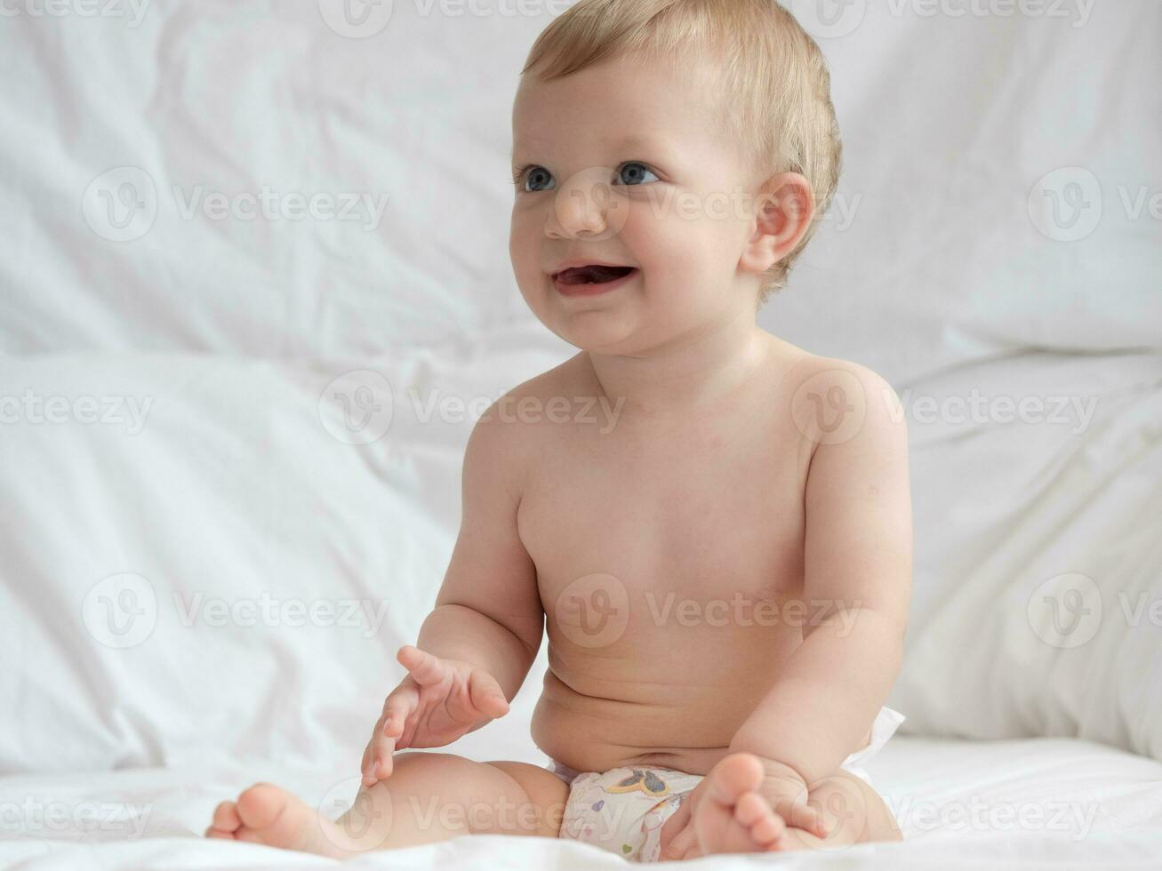 mignonne bébé séance et souriant sur le lit photo