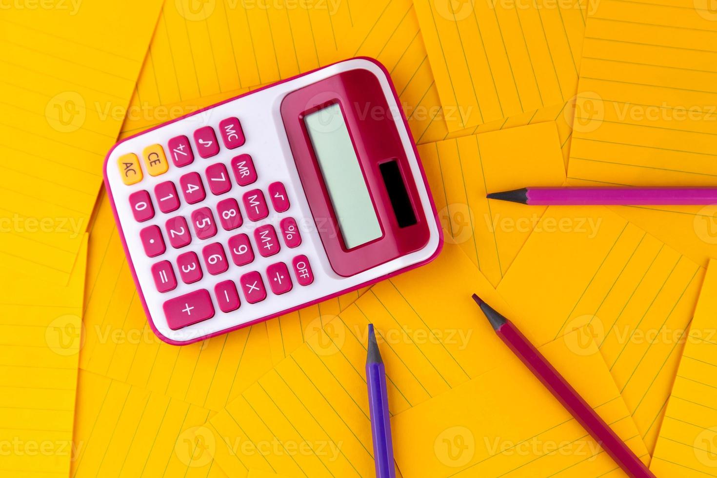 calculatrice sur feuilles de papier orange avec un crayon photo