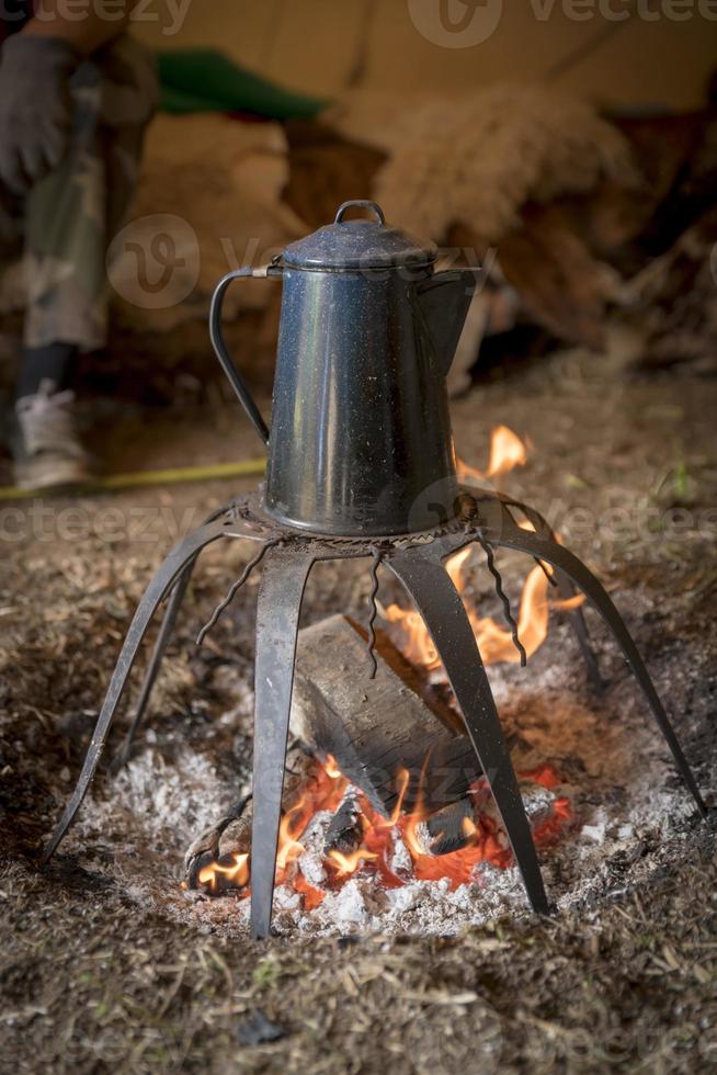 Une vieille cafetière en métal se dresse sur un feu de camp photo