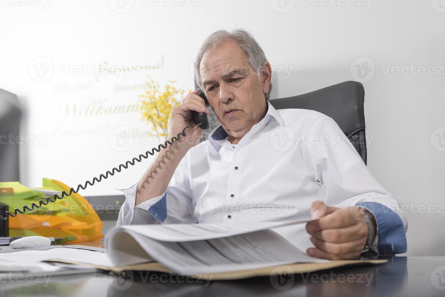 homme aîné, à, chemise blanche, téléphoner et faire défiler dans un fichier photo