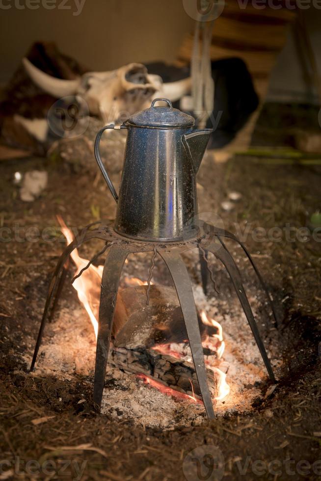 Ancienne cafetière en métal se dresse sur un feu de camp sur une grille photo