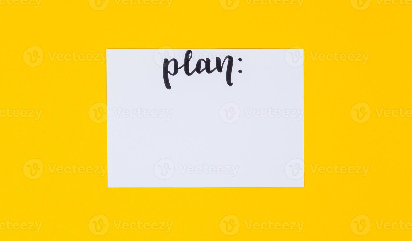 papier blanc vierge et inscription calligraphique noire du mot plan sur fond jaune photo