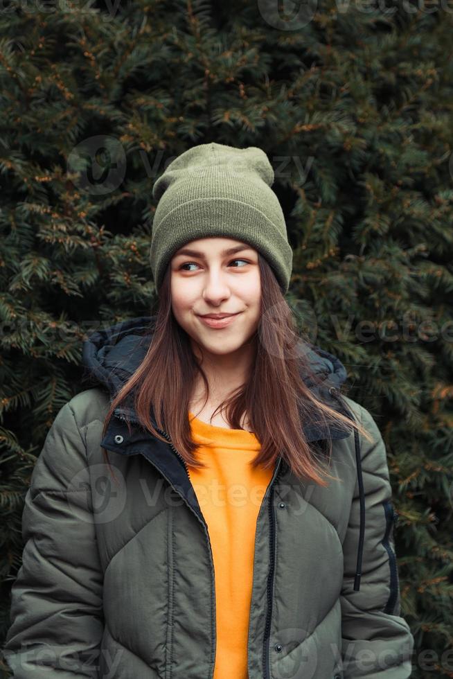 Portrait vertical d'une belle jeune fille souriante dans un pull jaune et un chapeau kaki photo