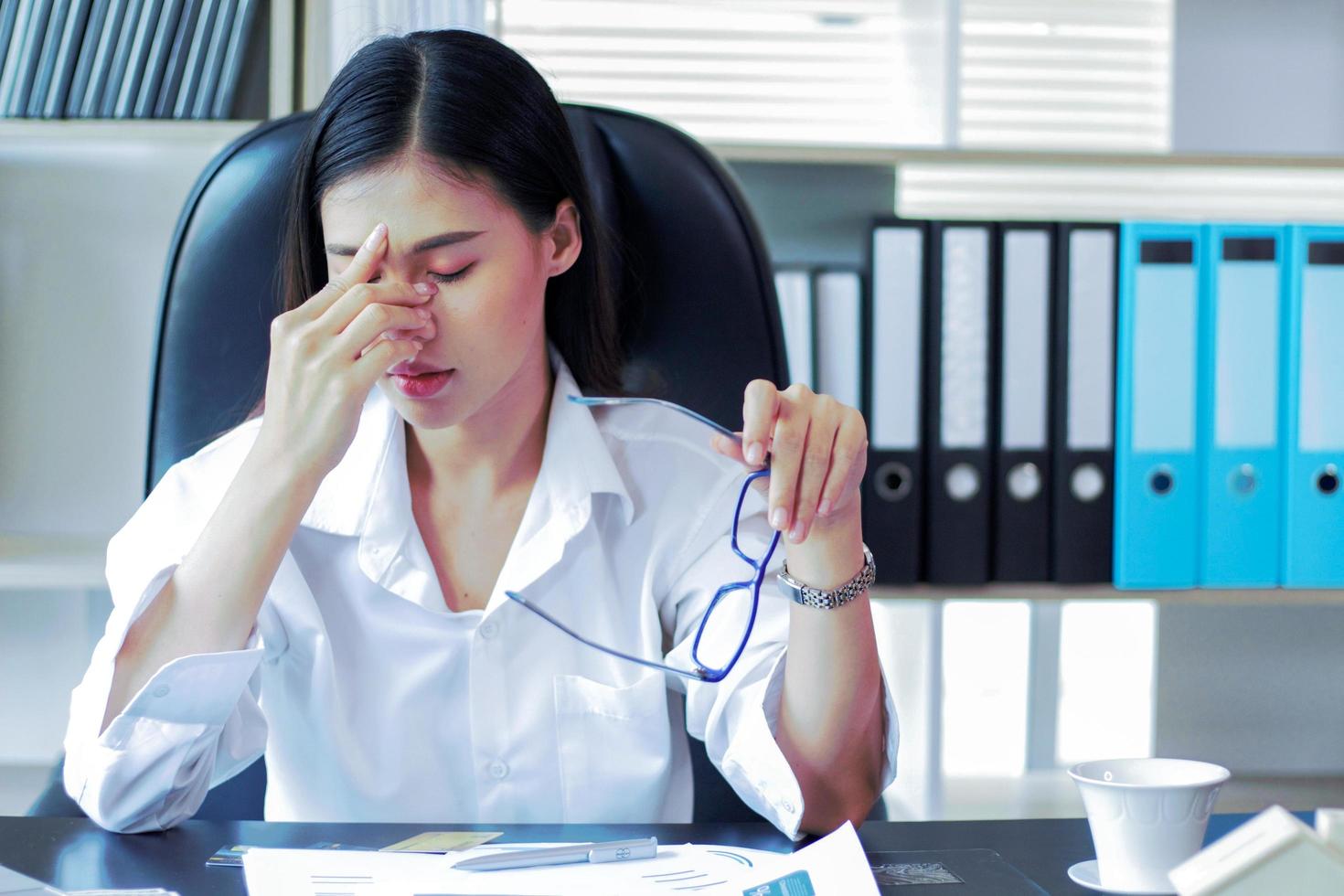 femme d'affaires asiatique fatiguée et ayant la fatigue oculaire de travailler dur photo