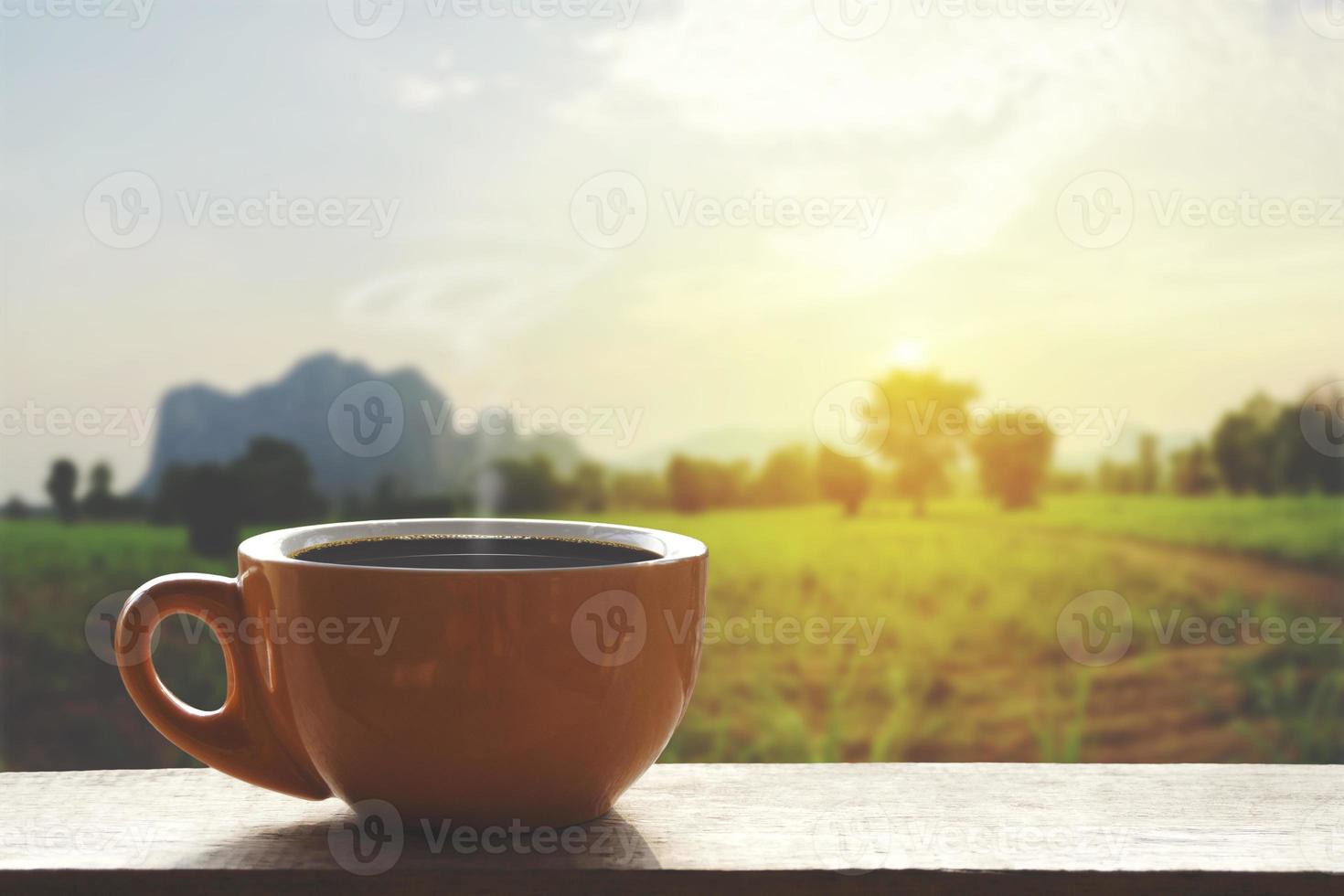 Café chaud noir avec de la fumée sur une table en bois avec un paysage de nature avec montagne photo