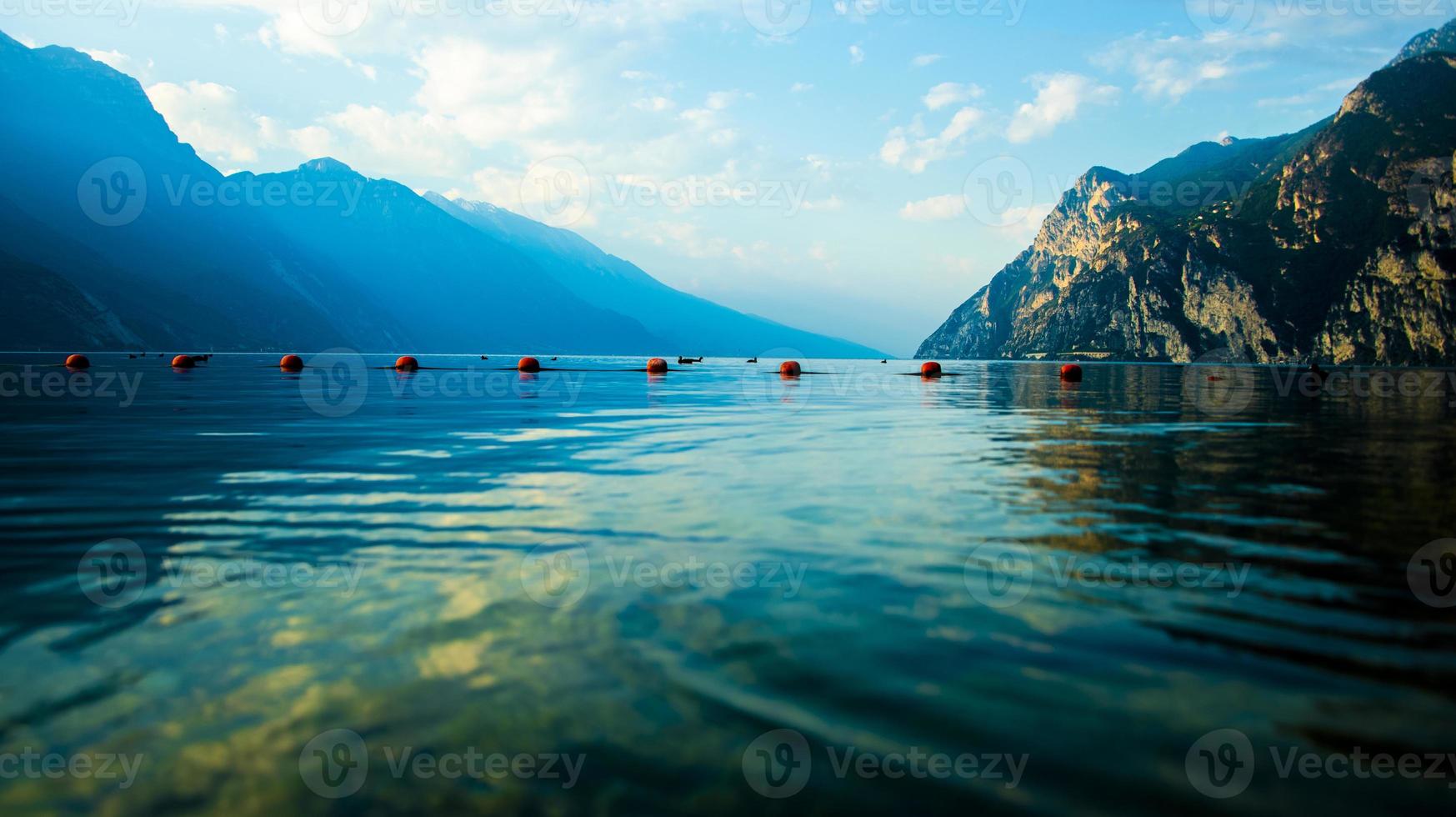 Le lac de garde avec des bouées rouges et des montagnes en toile de fond à Riva del Garda, Trento, Italie photo