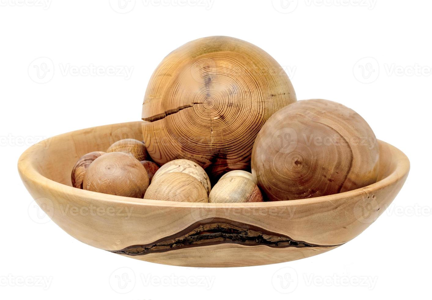 La main a tourné des boules en bois dans un grand bol isolé sur blanc photo
