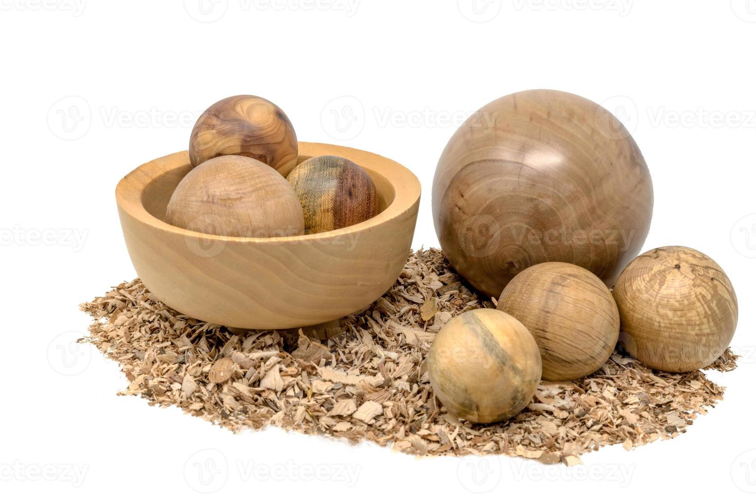 La main a tourné des boules de bois dans un bol décoré de sciure de bois isolated on white photo